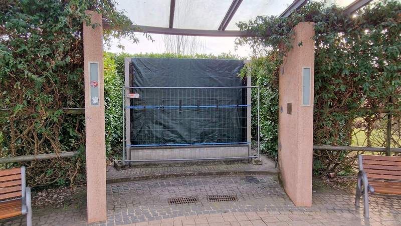 Zu kurz gedacht bei der Aufstellung des Mosaiks des lokalen Künstlers Hein Halfens bei der Neugestaltung des Kurpark-Eingangs vor einigen Jahren. Das Mosaik, das einst am Kurhaus Brehm angebracht war und das hat dem P-Platz am Haus des Gastes weichen müssen, wurde an der neuen, überdachten Sitzbank-Gruppe aufgestellt. Aber nicht unter dem Dach sondern wenige Zentimeter dahinter und ist seither Wind und Wetter ausgesetzt. Die Folge. Die bunten Steinchen purzeln. Seit einigen Wochen ist es nun provisorisch mit einer Plane abgedeckt. Auch das war ein Kraftakt, dieses der Gartenamtsleitung klar zu machen. Foto. rw. 