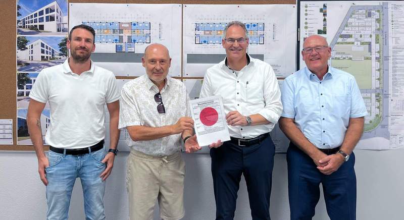 Landrat Dietmar Seefeldt (Zweiter von rechts) und SÜW-Wirtschaftsförderer Uwe König (rechts) überreichen Stefan Götz (links) und Geschäftsführer Dr. Karlheinz Weiss von der X2E GmbH den „Roten Punkt“ als offizielles Zeichen dafür, dass der Bau des neuen Firmenhauptsitzes in Rohrbach starten kann. Foto. X2E GmbH. Pressefrei.