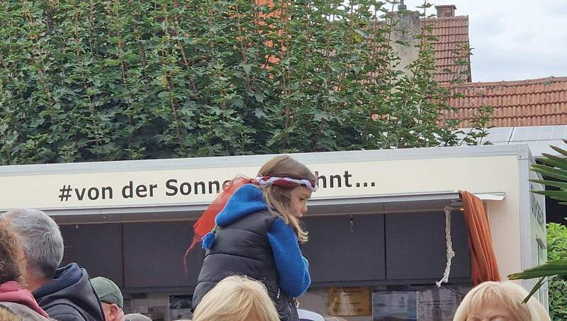 Treffender kann ein Schnappschuss kaum gelingen. Ein Kind auf den Schultern des Vaters vor dem Slogan der Südpfalz. "Von der Sonne verwöhnt". So war auch die Stimmung am heutigen Eröffnungstag des auch sehr familienfreundlichen Federweißenfestes in Dierbach. Foto. rw. 