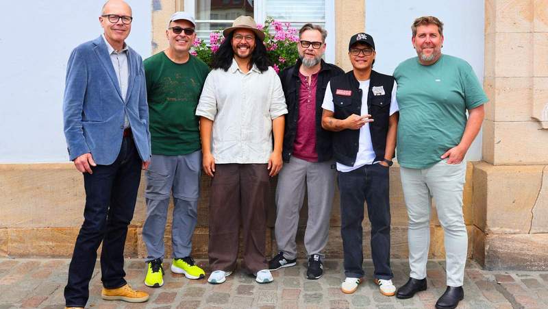 Freuen sich auf die Fête de la Musique in der LDer Innenstadt. OB Dominik Geißler (l.), Matthias Müller (2. v. l.), Jeffrey Deubler (3. v. l.) und Yods Pegoro (2. v. r.) von den Fuzo Groovers, die bei der Fête de la Musique auftreten werden, sowie Michael Fromm (3. v. r.) und Armin Schowalter (r.) von der Kulturinitiative Landau. Foto. Stadt. LD. Frei. 