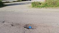 Ausschnitt der Schlagloch-Piste Friedrich-Ebert-Straße in BZA in Höhe des Schul-P-Platzes. Zum Größenvergleich haben wir mal eine herkömmliche P-Scheibe in das wohl größte Schlagloch vor Ort gelegt. Weitere Schlaglöcher gibt es zuhauf auf dem Weg weiter aufwärts zum benachbarten Hallenbad. Foto. rw. 