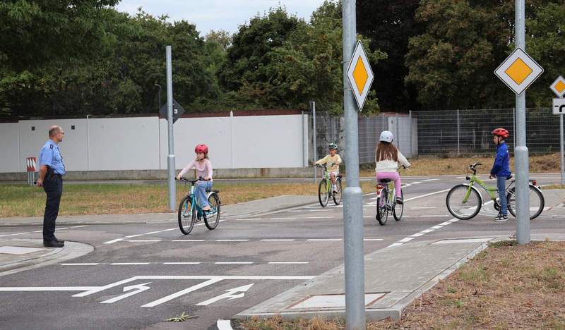 Verkehrssicherheitsberater Steffen Neu (links) von der Polizeiinspektion Landau unterrichtet die Kids auf dem neuen Verkehrsübungsplatz. Foto. Stadt. LD. Pressefrei. 