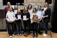 Beigeordnete Lena Dürphold (rechts) und die Leiterin der Kinder- und Jugendbibliothek Magdalena Schlosser (links) gemeinsam mit den Teilnehmenden des Lesewettbewerb-Regionalentscheids. Die Siegerin ist Hannah Kraus, Reihe vorne, Zweite von links. Foto. Stadt. LD. Frei.