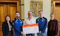 Bürgermeister Marcus Schaile (Bildmitte) übergibt im Beisein seiner Mitarbeiterinnen Melanie Weiß (links im Bild), die bei der Stadt Germersheim zuständig ist für die kommunale Sportstättenförderung, und Katharina Keller (rechts im Bild), stellvertretende Leiterin der Finanzabteilung, den willkommenen Spendenscheck an den 1. Vorsitzenden Adrian Pfeifer (2.v.l.) und den 2. Vorsitzenden Daniel Fürholzer (2.v.r.) vom FV GER. Foto. Smohr. Stadt GER. Frei. 