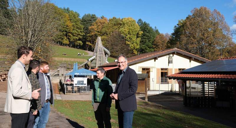 Tauschten sich zur PV-Anlage aus, die rechts auf dem Dach des Verwaltungsgebäudes zu sehen ist: Leon Pabst, Referatsleiter Zentrales Gebäudemanagement, Steven Barth, Abteilungsleiter „Bauen & Umwelt", Mitarbeiter Philipp Herrling (alle Kreisverwaltung), Wildpark-Geschäftsführer Daniel Kraus und Landrat Dietmar Seefeldt (von links). Im Hintergrund das Dach der Gaststätte, auf dem die Anlage erweitert werden soll. Foto. KV SÜW.
