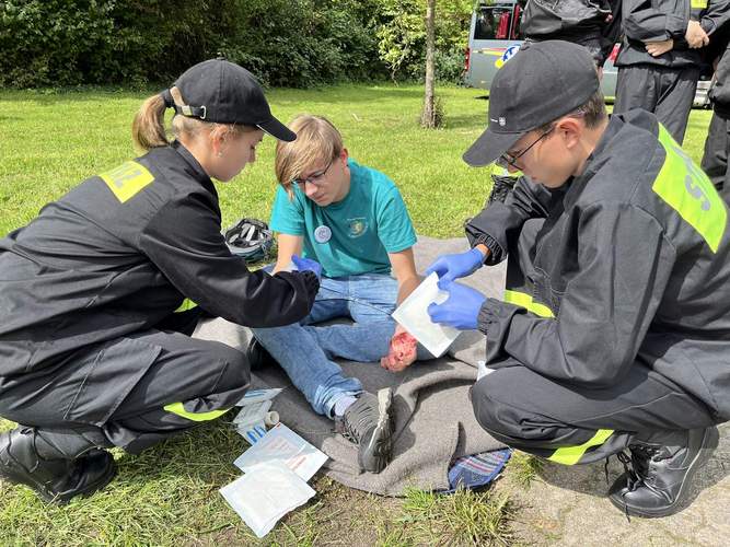 Zwei Mitglieder der polnischen Jugendfeuerwehr aus Oświęcim übten Erste Hilfe bei einem Jugendlichen des Jugendrotkreuzes nach einem angenommenen Fahrradunfall. Die Schürfwunden auf seiner Hand waren nur geschminkt. Foto. KV. SÜW. Frei. 