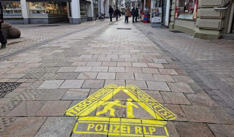 Mit "Aufpass"-Emblemen auf dem Straßenbelag weist die Polizei in NW Passanten darauf hin, sensibel in Bezug auf Taschendiebe zu sein. 