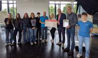 Landrat Dietmar Seefeldt (Dritter von rechts) und SÜW-Klimaschutzmanagerin Agnes Bartmus (Vierte von rechts) gratulieren dem Gewinner des Schulradelns, dem Gymnasium Edenkoben, mit einem Scheck. Foto. Gymnasium Edenkoben. Pressefrei. 