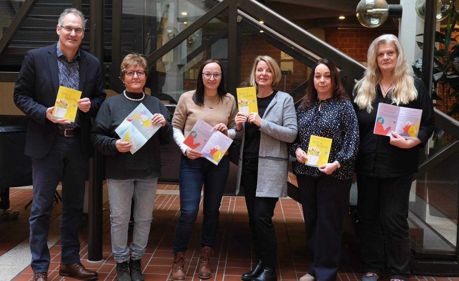 Präsentieren das Programm 2026 von „Brot und Rosen" (von rechts). Die Gleichstellungsbeauftragten Inge Keller (VG Annweiler am Trifels), Nicole Kruppenbacher (VG Offenbach an der Queich), Isabelle Stähle (Kreis SÜW), Sandra Hubert (VG Landau-Land) und Marita Rothmann (VG BZA) mit Landrat Dietmar Seefeldt. Auf dem Foto fehlt Stephanie Heikamp (VG Herxheim). Foto. KV. SÜW. Frei. 