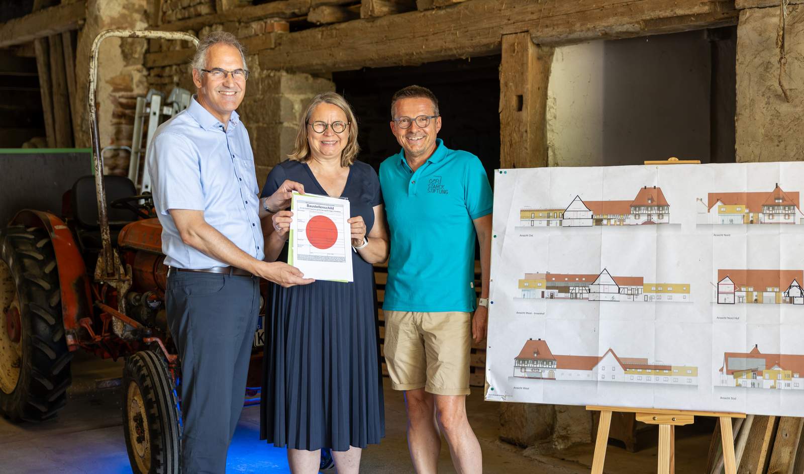 Landrat Dietmar Seefeldt hat Astrid und Georg Starck die Baugenehmigung für den Pflegebauernhof „Hofgut Böhlwiesen“ persönlich überreicht. Rechts im Bild sind die Pläne für das Bauvorhaben zu sehen. Foto. Starck-Stiftung- Pressefrei.