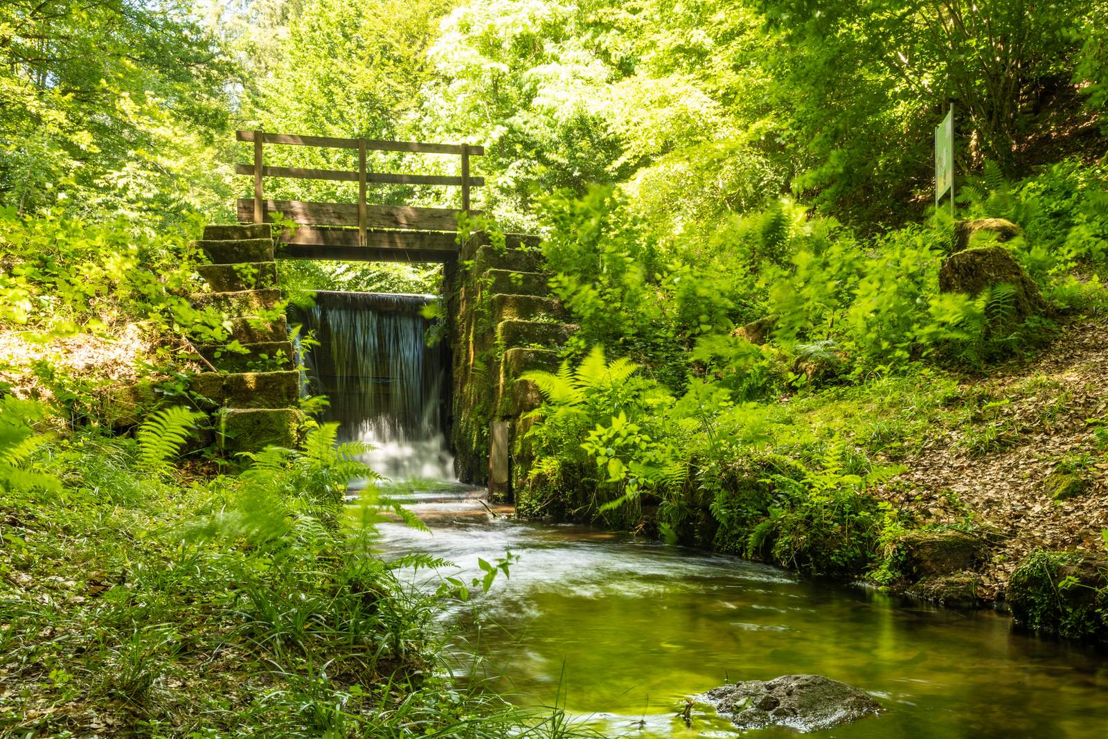 Das Wehr staut das Wasser. Wird es geöffnet rauschen die Baumstämme durch die Wasserkraft den Bach hinab. 